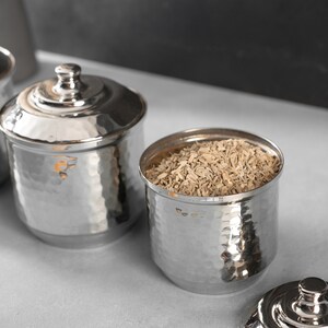 May include: Three silver hammered metal containers with lids. One container is filled with dried fennel seeds.