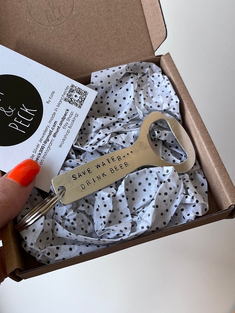 May include: A silver bottle opener with a black keychain ring. The bottle opener has the text "Save Water... Drink Beer" engraved on it.