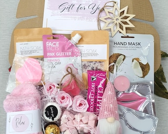 May include: A gift box filled with self-care items. Includes pink socks, bath soak, face mask, hot chocolate, a gnome, and a wooden snowflake. The box has a card that says "Gift for You".