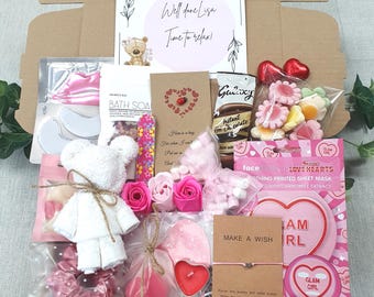 May include: A gift box filled with self-care items. Includes a teddy bear, bath soap, face mask, chocolates, marshmallows, a candle, and a bracelet. The box has a card that says "Well done Lisa, Time to relax!"
