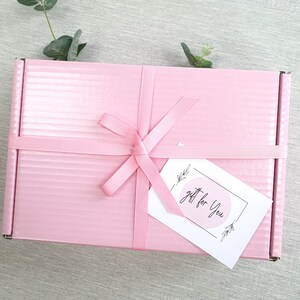 May include: A pink gift box with a white ribbon and bow. A white gift tag with black text and a circle design reads "gift for you".