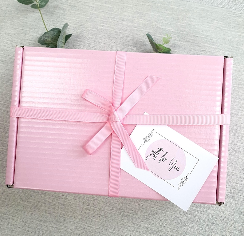 May include: A pink gift box with a white ribbon and bow. A white gift tag with black text and a circle design reads "gift for you".