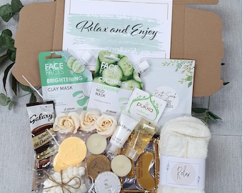 May include: A gift box containing Face Facts clay and mud masks, a Galaxy hot chocolate packet, marshmallows, two tea light candles, three cream-colored artificial roses, a Pukka tea bag, bath soak, lotion, gold eye patches, and white fuzzy socks.