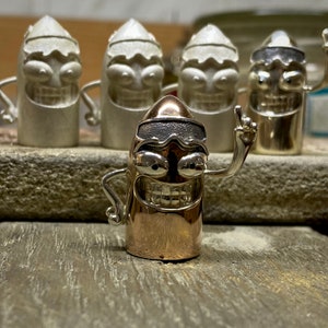 May include: A group of five silver and gold bullet-shaped figurines with cartoon faces. The figurine in the center is gold and has a silver ski mask. The other four figurines are silver and have cartoon faces.
