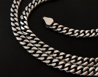 May include: A silver curb chain necklace with a thick, chunky design. The chain is made of interlocking links that create a bold and stylish look.