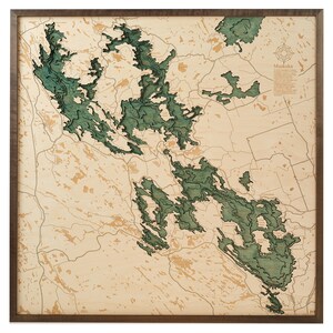 May include: A wooden map of the Muskoka region of Ontario, Canada. The map is laser-cut and features a detailed representation of the lakes and islands in the area. The map is painted in shades of green and brown, and is framed in a dark wood frame.