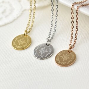 Puede incluir: Tres collares con diseños de colgantes de brújula. Uno es dorado, otro plateado y el tercero de oro rosa. Cada colgante tiene un diseño de estrella con coordenadas y texto grabados. Las cadenas son delicadas y los colgantes son ovalados.