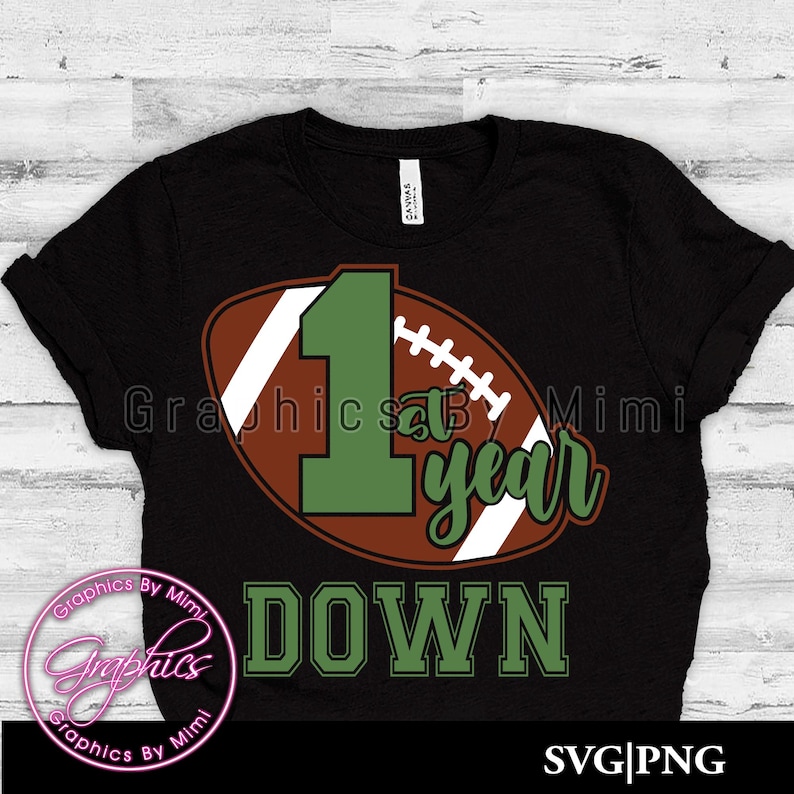 May include: Black t-shirt with a green number one and the words "1st year down" on a brown and white football graphic.