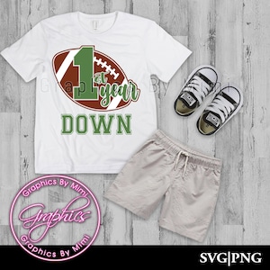 May include: White t-shirt with a brown and green football graphic and the text "1st year down".