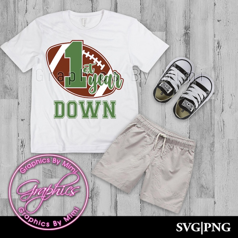 May include: White t-shirt with a brown and green football graphic and the text "1st year down".