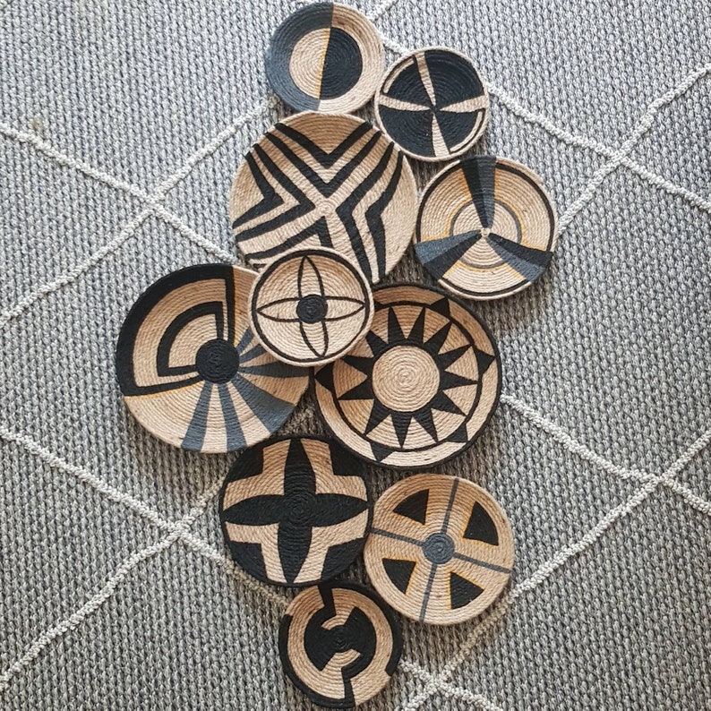May include: A set of nine black and white woven wall decor pieces with geometric patterns. The pieces are round and have a natural fiber texture.