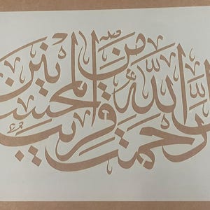 May include: A white stencil with Arabic calligraphy. The calligraphy is in a traditional style and is arranged in a circular pattern. The stencil is made of a durable material and is designed for use with paint or other mediums.