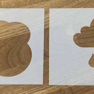 Puede incluir: Dos plantillas blancas, una con forma de nube y la otra con una nube y gotas de lluvia. Las plantillas están sobre una superficie de madera.