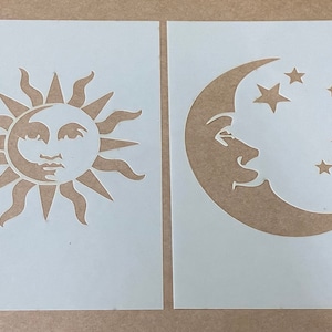 Puede incluir: Dos plantillas blancas, una con un sol y la otra con una luna creciente y estrellas. El sol tiene una cara y la luna tiene una cara.