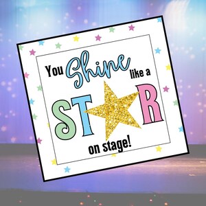 May include: A square sign with a white background and a border of small colourful stars. The text reads You Shine like a STAR on stage! The word Shine is in blue script, and the letters S, T, and R are in pastel colours with a gold glitter star.