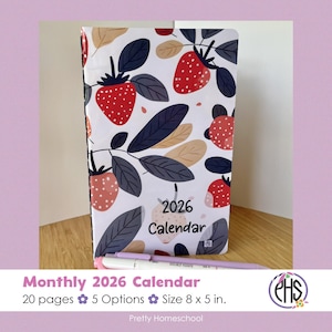 Peut inclure: Un calendrier mensuel 2026 avec un motif de fraises et de feuilles. Le calendrier mesure environ 20 x 13 cm et comporte le texte "2026 Calendar". Un stylo rose et blanc repose devant le calendrier. Le texte "Monthly 2026 Calendar" est en bas.