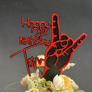May include: Black and red cake topper with the text "Happy 21st Birthday Tom" and a red hand making the rock and roll sign.