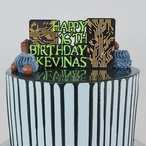 Könnte beinhalten: Eine blaue und schwarze Drip-Torte mit einem schwarzen und goldenen Platinen-Design-Topper, auf dem "Happy 16th Birthday Kevinas" steht.