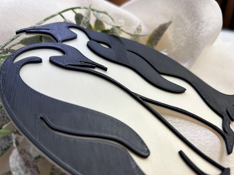 May include: A black and white 3D printed wall decoration with a wavy design. The design is reminiscent of a stylised flame or wave.
