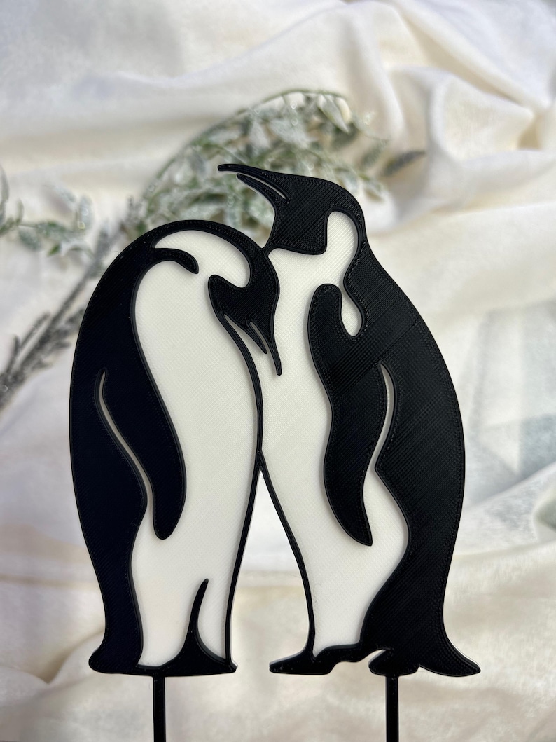 May include: A black and white 3D printed penguin couple figurine. The penguins are standing close together, with their heads touching. The figurine is a romantic and whimsical decoration for a home or office.