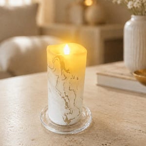 May include: A cylindrical LED pillar candle featuring a white and gold marbled pattern. The top of the candle emits a warm, glowing yellow light, and the base rests on a clear, circular glass plate, creating a steady, flameless illumination.
