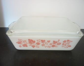 May include: White glass baking dish with a pink and white floral design. The dish has a lid with a ribbed pattern.