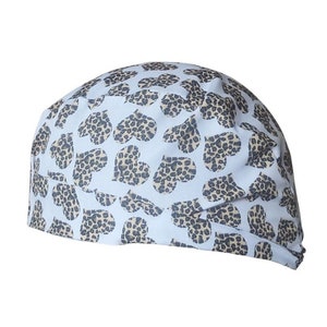 Puede incluir: Un gorro de quirófano blanco con un patrón de corazones de estampado de leopardo marrón.