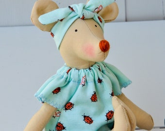 Könnte beinhalten: Ein handgemachtes Plüschtier in Form einer Maus, das ein hellblaues Stirnband mit Marienkäfer-Druck und ein hellblaues Kleid mit Marienkäfer-Druck trägt.