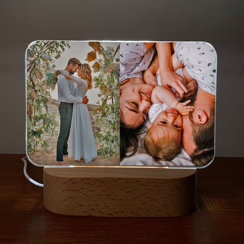 Op de afbeelding: Een houten fotolijst met een transparant acryl inzetstuk. De lijst toont twee foto's, een van een stel dat elkaar omhelst en de andere van een gezin met een baby.