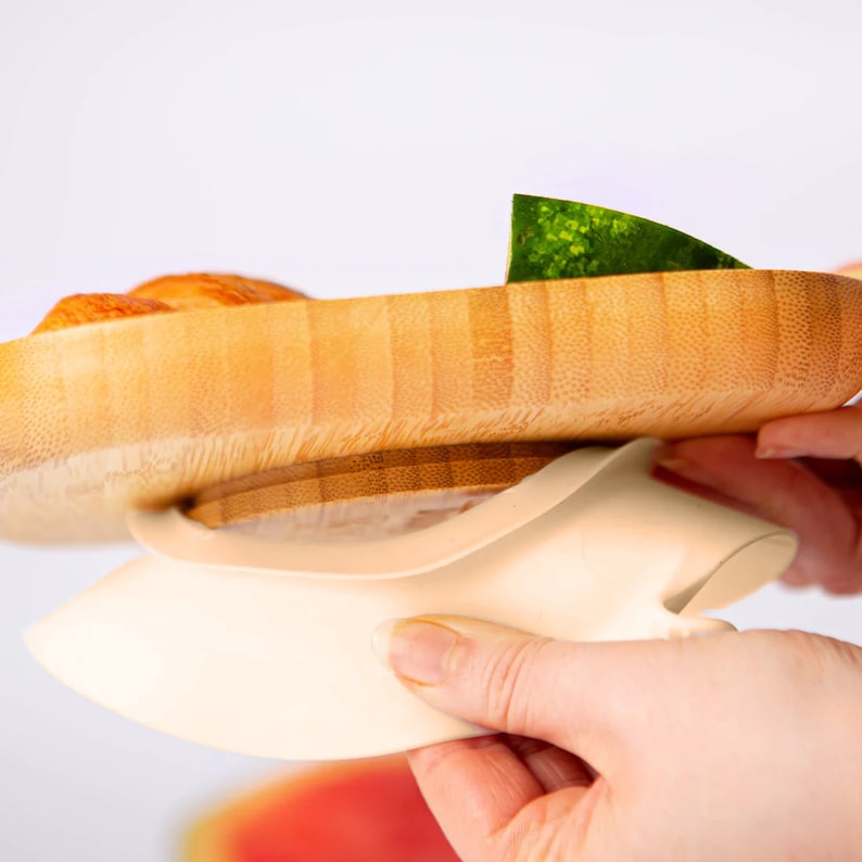 Peut inclure: Un attrape-nourriture en silicone blanc avec une assiette en bambou sur le dessus. L'attrape-nourriture en silicone est con&ccedil;u pour attraper les aliments qui tombent de l'assiette.