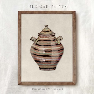 Pode incluir: Uma ilustração vintage de um jarro de cerâmica listrado com tampa. O jarro é pintado em tons de marrom, rosa, verde e preto. A imagem é emoldurada em uma moldura de madeira marrom. "Old Oak Prints" e "Remastered Vintage Art" estão impressos abaixo da imagem.