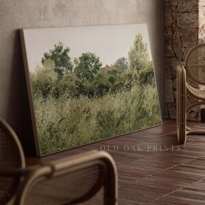 May include: A painting depicting a green field with trees in the background. The painting is framed and hanging on a wall.