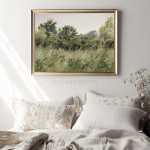 May include: A framed painting depicting a landscape with green trees and a field of tall grass. The painting is in a gold frame and is hanging on a white wall.