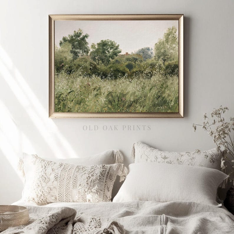 May include: A framed painting depicting a landscape with green trees and a field of tall grass. The painting is in a gold frame and is hanging on a white wall.