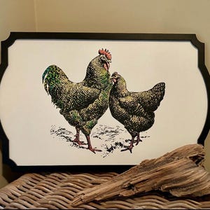 May include: A black framed print with a white background featuring a green and black rooster and hen. The rooster has a red comb and wattle.