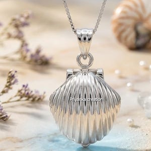 Op de afbeelding: Een zilveren schelpenhanger ketting. De hanger is een gedetailleerd, geribbeld clamshell-ontwerp dat opengaat. De ketting is een fijne zilveren boxketting. De tekst "Priyanka creation" is zichtbaar.