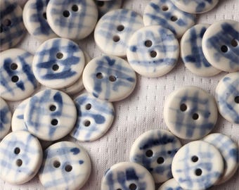 May include: A collection of white ceramic buttons with a blue and white checkered pattern. The buttons are round and have two holes.