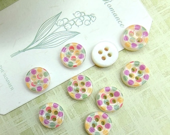 May include: A collection of eight round, four-hole buttons. Seven buttons feature a translucent base with a pattern of small, multicolored polka dots in pink, green, and orange. One button is solid opaque white. The buttons are arranged on a card.