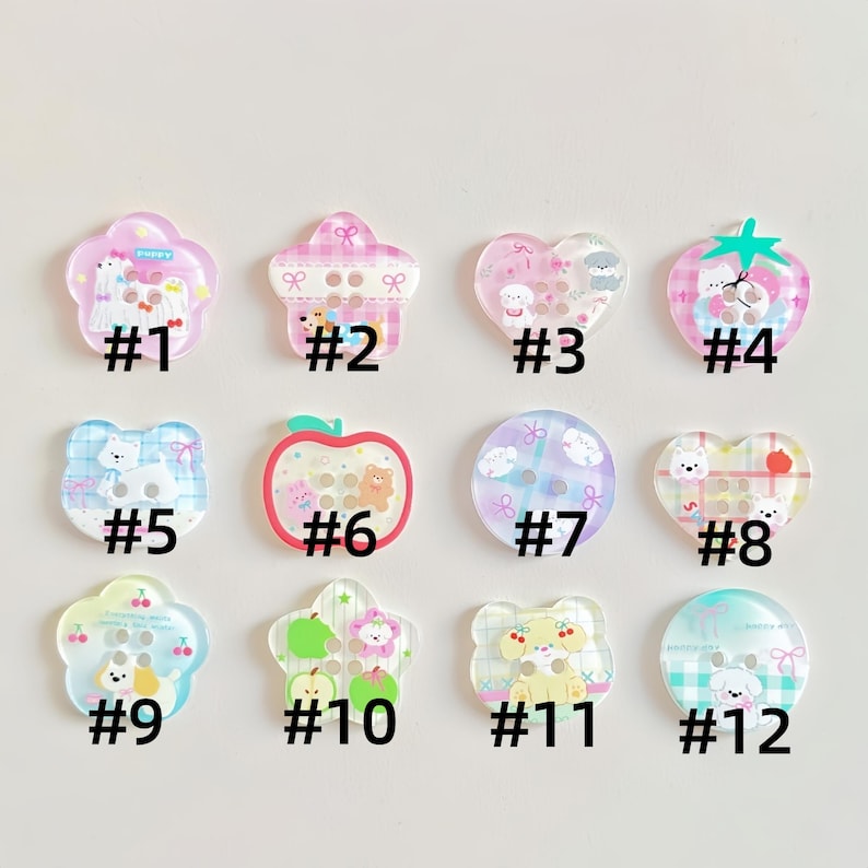 May include: A collection of twelve assorted acrylic buttons in various shapes including flowers, hearts, circles, and apples. Each button features colorful cartoon illustrations of puppies, bears, and fruit, labeled with numbers one through twelve.