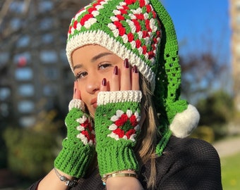 May include: A green, red and white crocheted hat with a long, pointed top and a pom-pom. The hat is paired with matching fingerless gloves.