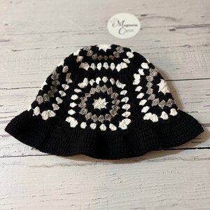 May include: A black, white, and gray crochet bucket hat with a granny square pattern.