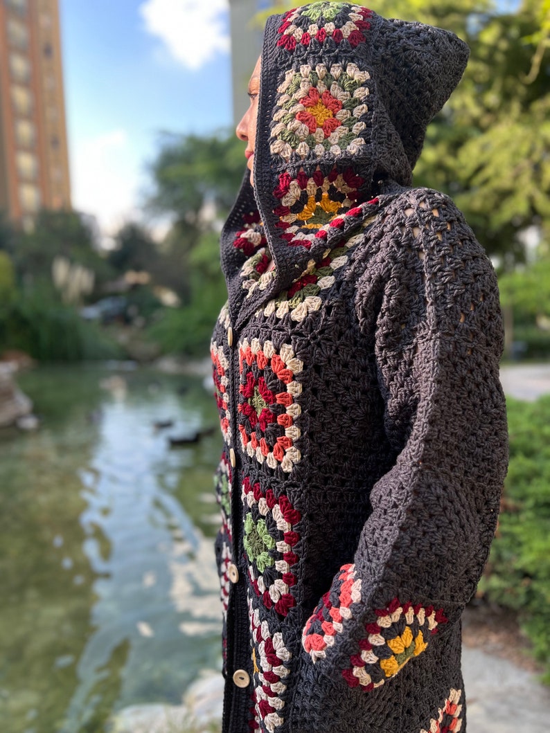 May include: A gray crocheted cardigan with a hood featuring colorful granny squares. The cardigan has a button closure and pockets.
