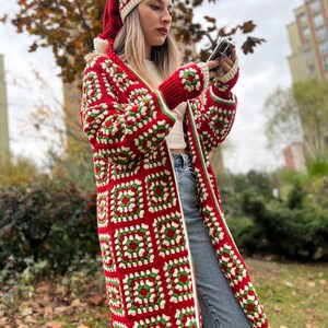 May include: A red, white, and green crochet cardigan with a matching hat. The cardigan has a long, loose fit and is made with a granny square pattern.