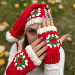 May include: Red and white crocheted fingerless gloves with green accents. The gloves feature a granny square pattern.