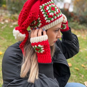 May include: Red and green crocheted hat with a white pom-pom and matching fingerless gloves.