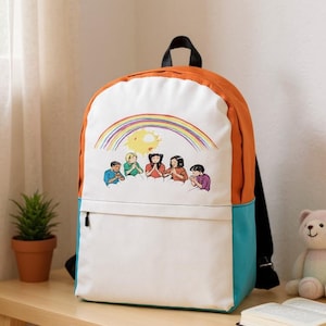 Puede incluir: Una mochila colorida con un panel frontal blanco con una ilustración de dibujos animados de un arcoíris, un sol y figuras. La mochila tiene paneles laterales naranjas y turquesas, correas negras y una cremallera negra.
