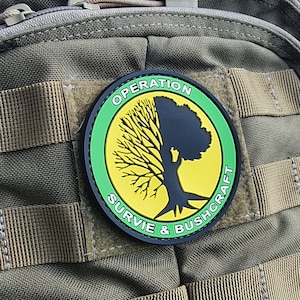 Puede incluir: Una mochila táctica verde con un parche amarillo y verde que dice "Operación Sobrevivir y Bushcraft".