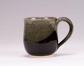 May include: A ceramic mug with a black and green glaze. The mug has a rounded body and a handle.