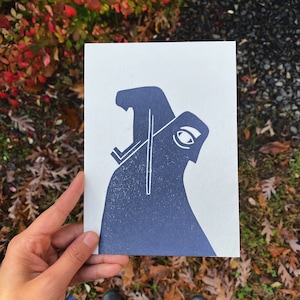 May include: A blue and white linocut print of a stylized figure with a large eye.