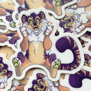 May include: A sticker featuring a cartoon tiger with purple and green stripes, white fur, and a happy expression. The tiger is wearing a necklace and has its paws raised in the air.